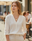 Woman wearing a white blouse and beige pants in an outdoor setting